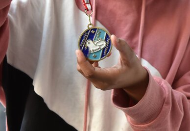 La médaille créée par l'école Jules-Ferry La médaille créée par l'école Jules-Ferry représente un oiseau sur fond bleu, entouré des mentions : progrès, unité, liberté, apprendre