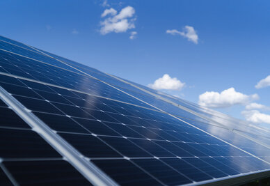 Panneaux photovoltaïques au sol inclinés vers le ciel, reflétant la lumière solaire par temps ensoleillé