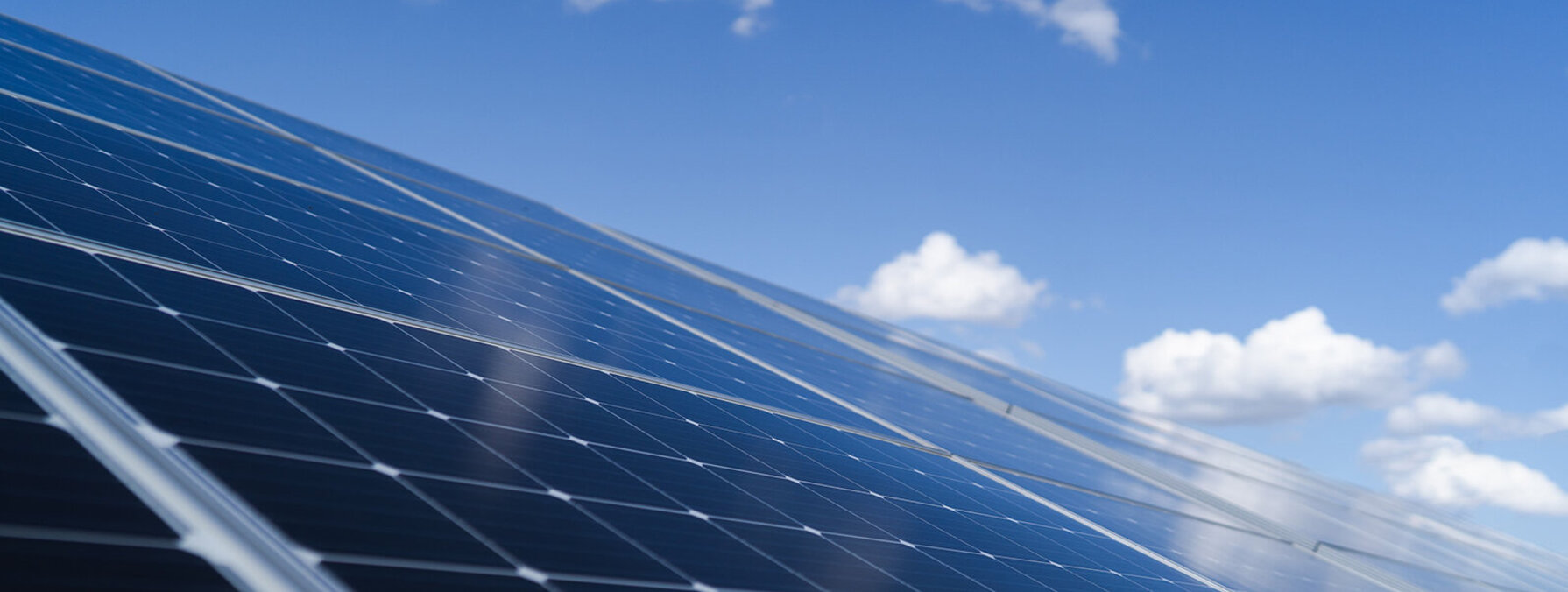 Panneaux photovoltaïques au sol inclinés vers le ciel, reflétant la lumière solaire par temps ensoleillé