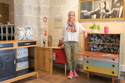 L'artisane de l'Atelier de Cilou pose au milieu de meubles vintage relookés aux tiroirs multicolores