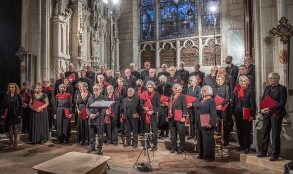 Chœur en concert dans une église gothique, choristes en tenue noire et rouge tenant leurs partitions - Agrandir l'image, fenêtre modale