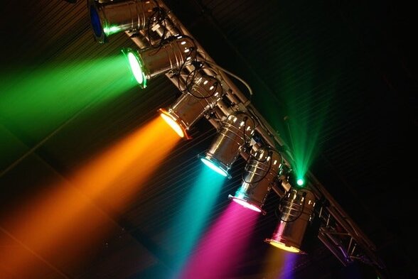 Projecteurs de scène sur perche diffusant des faisceaux lumineux colorés dans l'obscurité d'un plateau de théâtre - Agrandir l'image, fenêtre modale