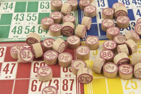 Tonnelets numérotés en bois éparpillés sur des cartons de loto colorés verts, rouges et jaunes - Agrandir l'image, fenêtre modale
