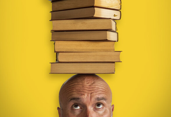Homme chauve regardant une haute pile de livres en équilibre sur sa tête, sur fond jaune vif - Agrandir l'image, fenêtre modale