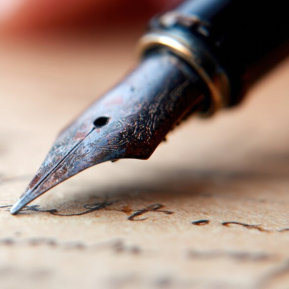 Plume d'un stylo-plume ancien en gros plan sur un parchemin couvert d'écriture manuscrite - Agrandir l'image, fenêtre modale