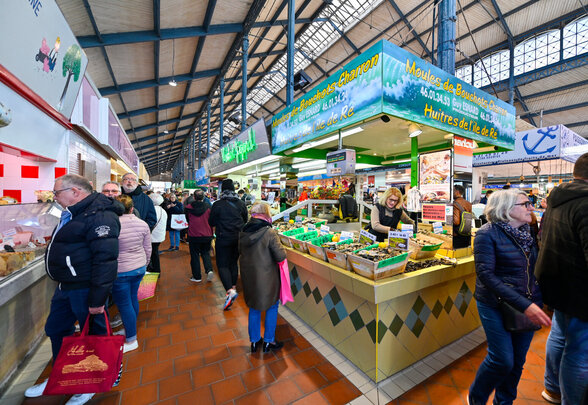 Allée animée d'un marché couvert avec visiteurs et étal de moules et huîtres de l'île de Ré - Agrandir l'image, fenêtre modale