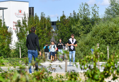 Étudiants marchant sur l'allée du Pôle Universitaire Niortais, bâtiment de l'Université de Poitiers visible en arrière-plan