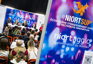 Intervenants en tribune face au public lors du salon de l'enseignement supérieur à l'Acclameur, signalétique Niort Agglo #NiortSup' visible au premier plan