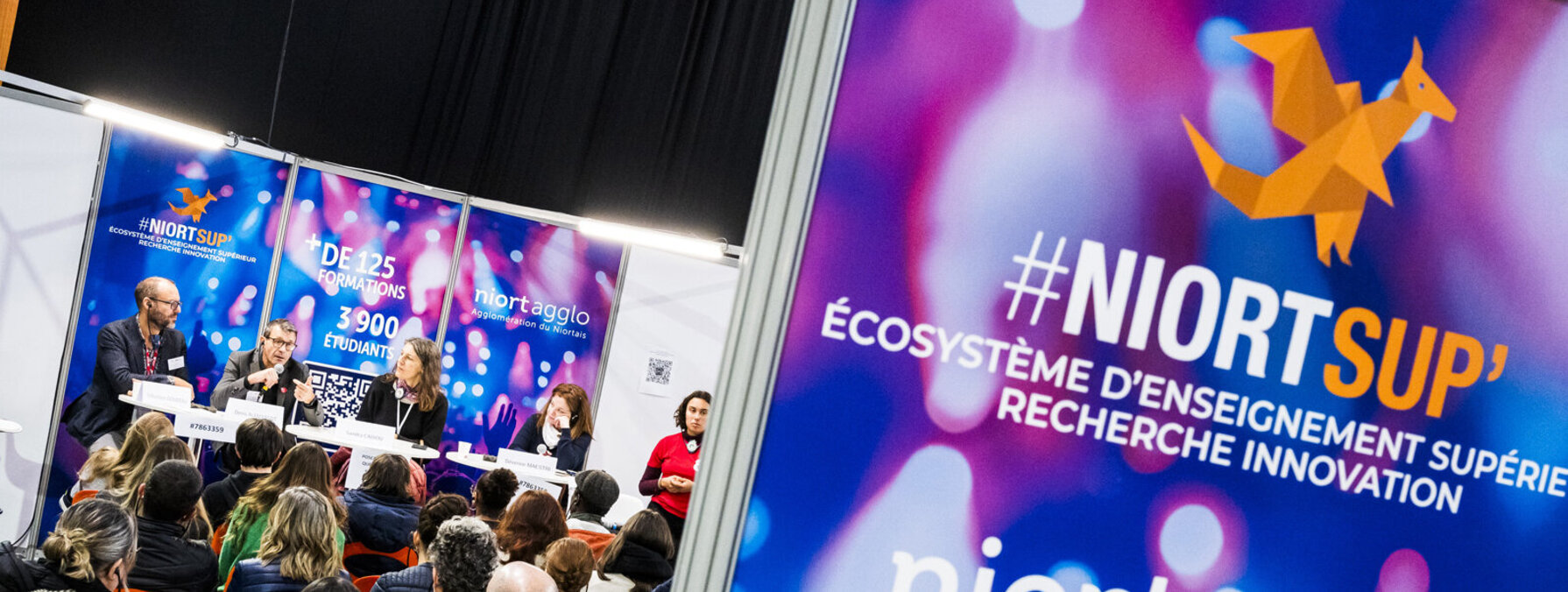 Intervenants en tribune face au public lors du salon de l'enseignement supérieur à l'Acclameur, signalétique Niort Agglo #NiortSup' visible au premier plan