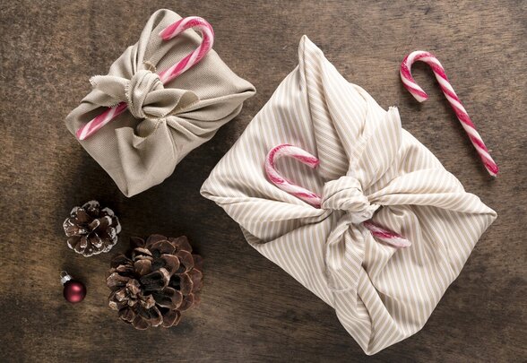 Deux cadeaux emballés dans du tissu naturel façon furoshiki, décorés de pommes de pin et cannes de bonbon - Agrandir l'image, fenêtre modale