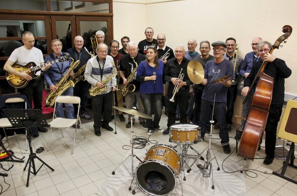 L'orchestre au complet : une vingtaine de musiciens tenant saxophones, trompettes, trombones, contrebasse et guitare, chanteuse incluse. - Agrandir l'image, fenêtre modale
