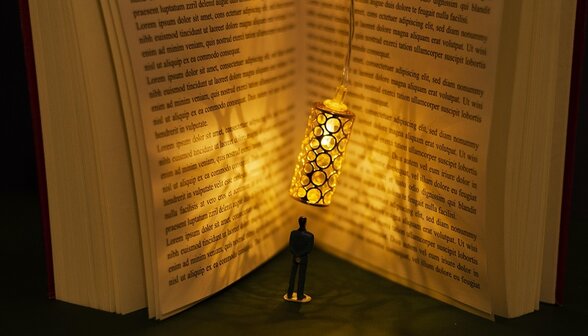 Silhouette miniature d'un lecteur debout entre les pages lumineuses d'un livre ouvert, évoquant l'immersion dans la lecture - Agrandir l'image, fenêtre modale