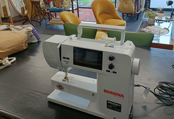 Machine à coudre Bernina posée sur un plan de travail dans un atelier de couture équipé - Agrandir l'image, fenêtre modale