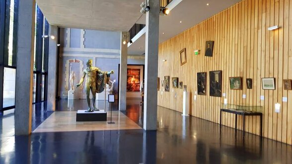 Salle des Beaux-Arts avec une grande statue en bronze au centre et des peintures accrochées sur un mur lambrissé de bois - Agrandir l'image, fenêtre modale