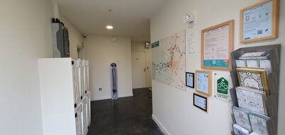 Intérieur de la halte : casiers blancs à gauche, borne de réparation vélo au fond, carte cyclable et label Accueil Vélo sur le mur
