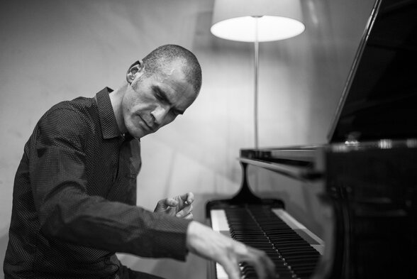 Melaine Dalibert jouant du piano à queue, penché sur le clavier dans une attitude de concentration - Agrandir l'image, fenêtre modale