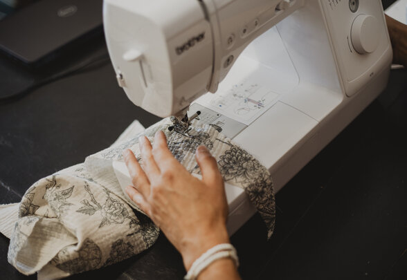Mains guidant un tissu à motifs floraux sous l'aiguille d'une machine à coudre Brother - Agrandir l'image, fenêtre modale