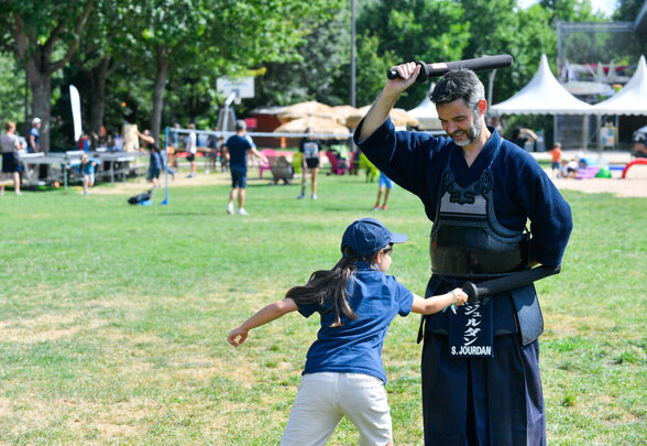 Un pratiquant de kendo en armure initie un enfant au maniement du sabre lors de Niort Plage - Agrandir l'image, fenêtre modale