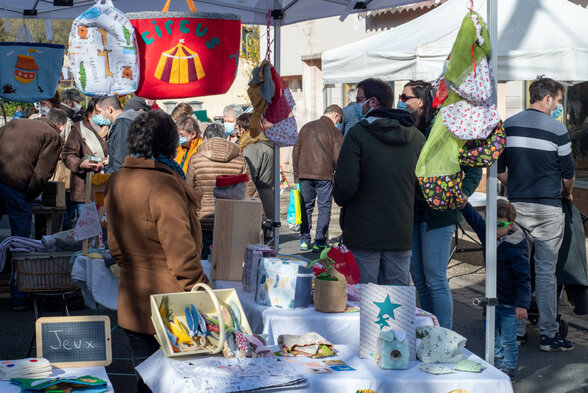 Étals de jouets et articles textiles animés par visiteurs et exposants sous des chapiteaux en plein air lors d'une édition précédente - Agrandir l'image, fenêtre modale