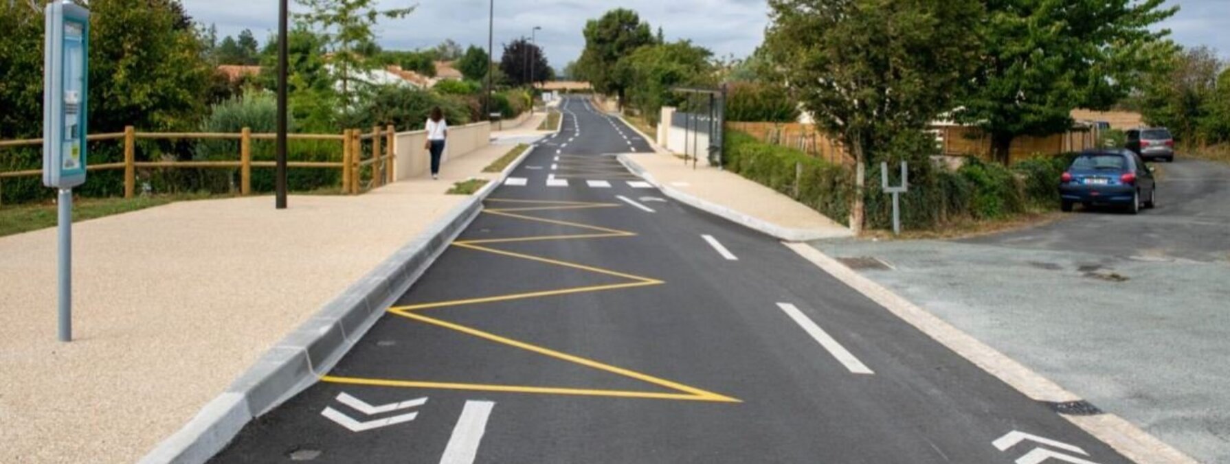 Voie cyclable aménagée avec marquage au sol jaune et blanc, séparée de la chaussée, longeant un arrêt de bus ligne 23