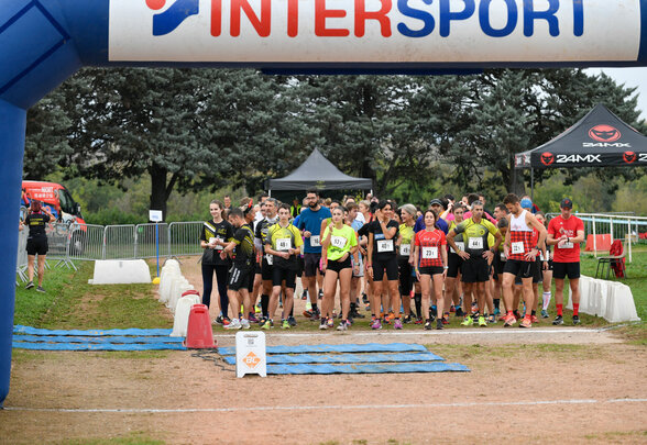 Coureurs avec dossards rassemblés sous l'arche de départ Intersport, prêts à s'élancer sur la piste - Agrandir l'image, fenêtre modale