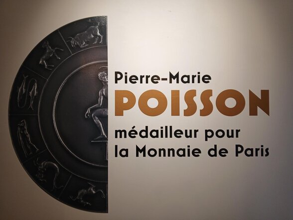Panneau d'exposition présentant une grande médaille en bronze gravée de figures zodiacales en relief - Agrandir l'image, fenêtre modale