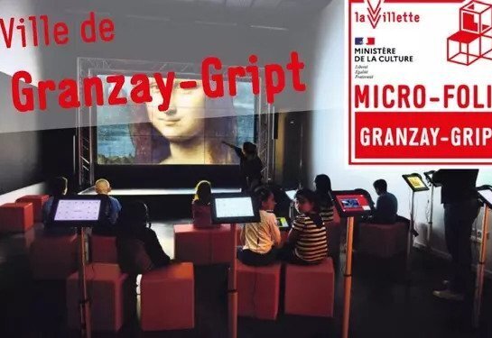 Visiteurs installés face à des tablettes tactiles dans l'espace Micro-Folie de Granzay-Gript, grand écran projetant la Joconde en arrière-plan - Agrandir l'image, fenêtre modale