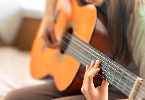 Gros plan sur les mains d'un musicien jouant de la guitare classique, doigts positionnés sur le manche - Agrandir l'image, fenêtre modale