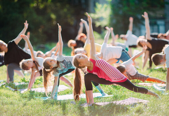 Enfants pratiquant la gymnastique en plein air sur des tapis, bras levés en position d'étirement - Agrandir l'image, fenêtre modale