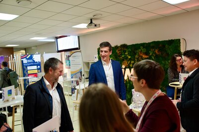 Jérôme Baloge, Maire de Niort, échangeant avec des participants au Salon INNN, devant des stands d'exposants et un mur végétal