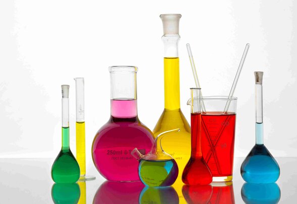Fioles et béchers de laboratoire remplis de liquides aux couleurs vives : vert, rose, jaune, rouge et bleu. - Agrandir l'image, fenêtre modale