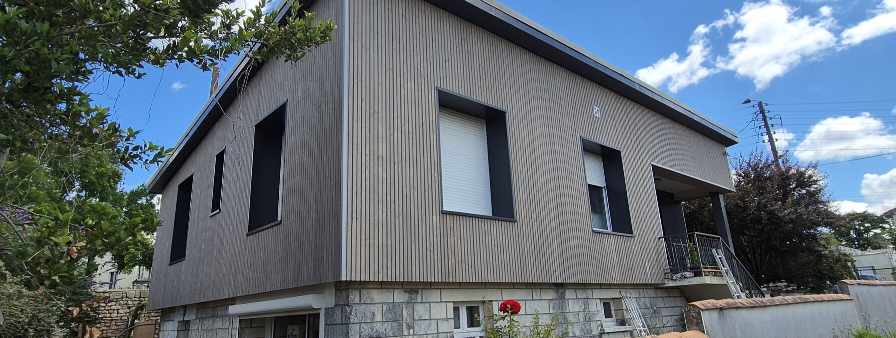 Maison individuelle rénovée avec isolation par l'extérieur, bardage gris posé sur la façade et nouveaux volets roulants