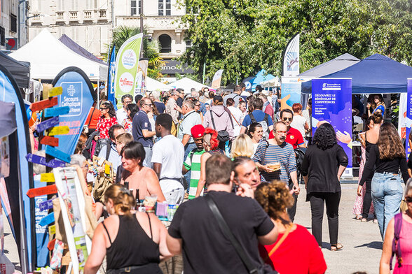 Foule de visiteurs déambulant entre les stands d'associations dans une rue du centre-ville ensoleillée - Agrandir l'image, fenêtre modale