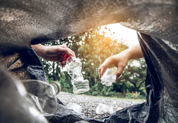 Deux mains déposant des bouteilles plastiques froissées dans un sac de collecte, cadrage depuis l'intérieur du sac - Agrandir l'image, fenêtre modale