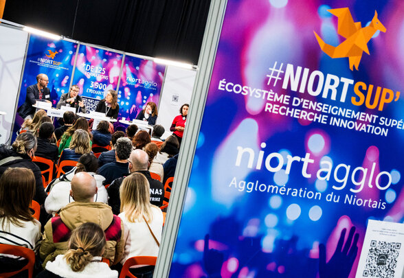 Intervenants en tribune face au public lors du salon de l'enseignement supérieur à l'Acclameur, signalétique Niort Agglo #NiortSup' visible au premier plan - Agrandir l'image, fenêtre modale