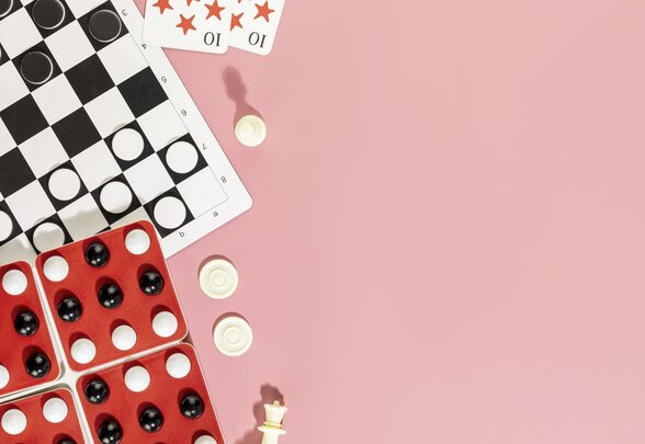 Échiquier avec pions de jeu de dames, pièces d'échecs, cartes à jouer et Puissance 4 sur fond rose - Agrandir l'image, fenêtre modale