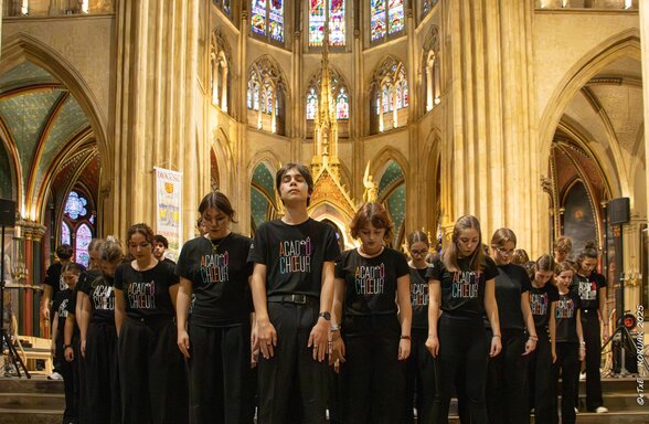 Les choristes d'ACAD'ÔCHŒUR en formation dans une nef gothique ornée de vitraux colorés - Agrandir l'image, fenêtre modale