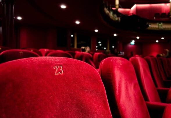 Salle de théâtre aux fauteuils en velours rouge, avec le siège numéro 23 au premier plan - Agrandir l'image, fenêtre modale