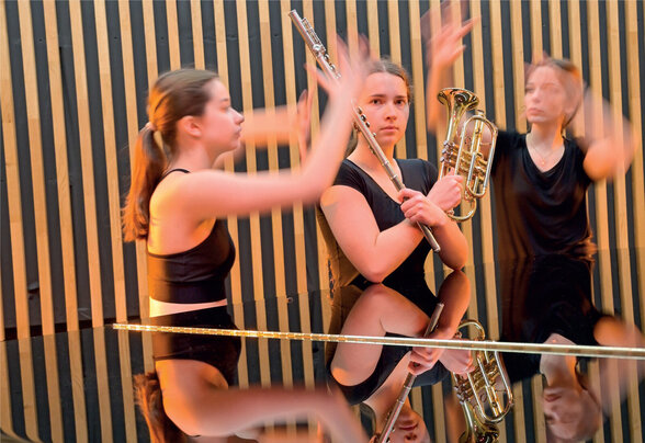 Élèves en prestation mêlant danse et instruments à vent, reflets sur le couvercle d'un piano à queue - Agrandir l'image, fenêtre modale