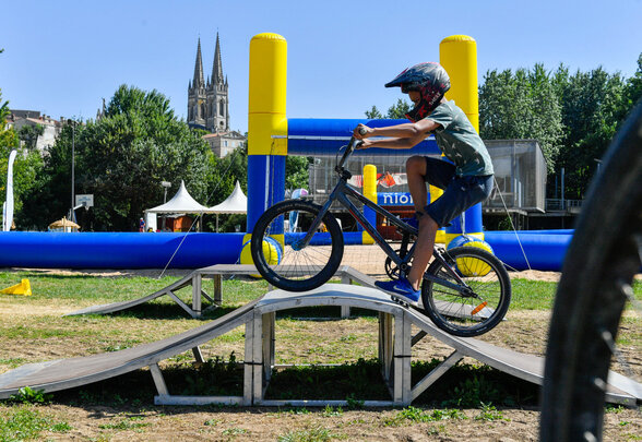 Enfant avec casque sur un vélo BMX franchissant une rampe en bois lors de Niort Plage - Agrandir l'image, fenêtre modale