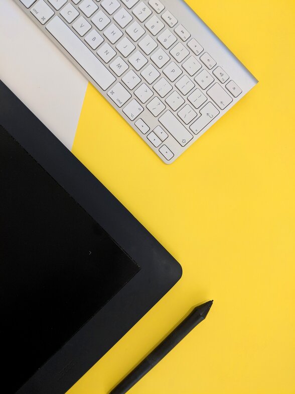 Clavier blanc, tablette numérique noire et stylet posés sur un fond jaune, symbolisant les outils du numérique - Agrandir l'image, fenêtre modale