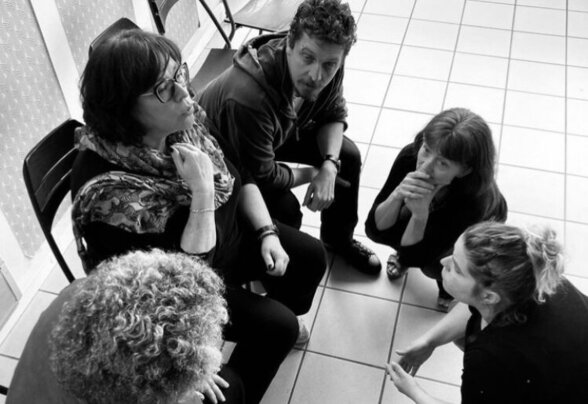 Cinq participants assis en cercle au sol et sur des chaises, concentrés lors d'un exercice de groupe - Agrandir l'image, fenêtre modale