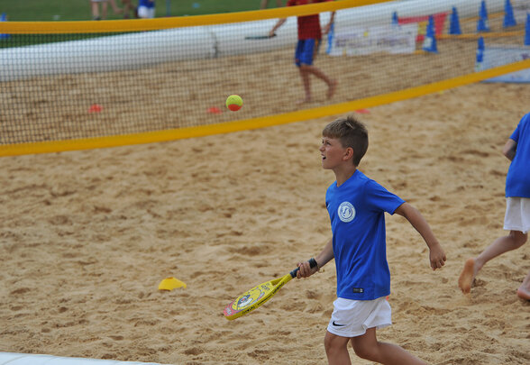 Enfant en maillot bleu jouant au beach tennis sur le sable, raquette à la main - Agrandir l'image, fenêtre modale