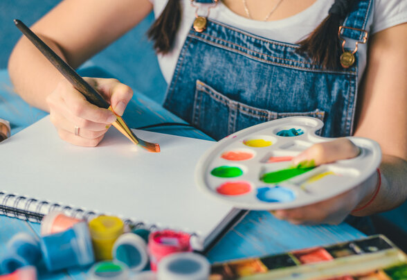Pretty smiling young woman drawing a picture with poster paint - Agrandir l'image, fenêtre modale