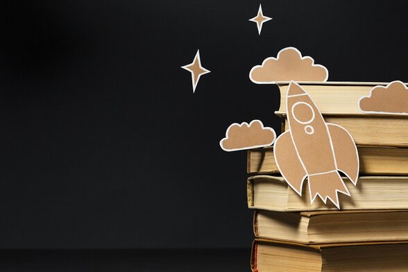 Pile de livres avec une fusée et des nuages en carton découpé évoquant l'imaginaire de la lecture enfantine - Agrandir l'image, fenêtre modale