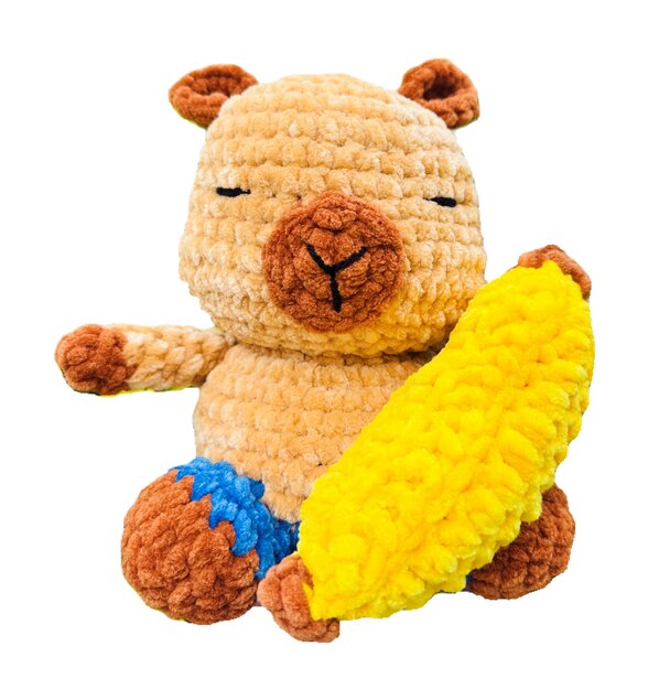 Peluche au crochet représentant un capybara tenant une banane jaune