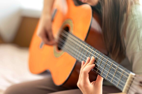 Gros plan sur les mains d'un musicien jouant de la guitare classique, doigts positionnés sur le manche - Agrandir l'image, fenêtre modale