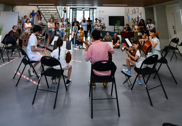Jeunes musiciens assis en cercle jouant guitare et violoncelle au Conservatoire devant un public de visiteurs - Agrandir l'image, fenêtre modale