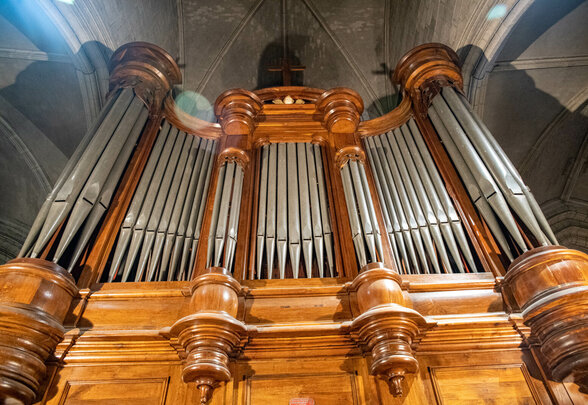 Grand buffet d'orgue en bois sculpté et ses tuyaux métalliques dans une église, cadré en contre-plongée - Agrandir l'image, fenêtre modale