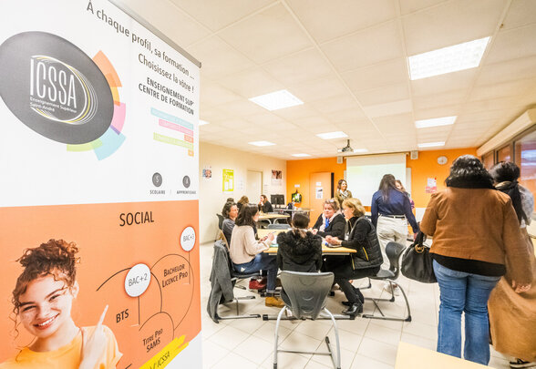 Participants et enseignants réunis en petits groupes d'échanges dans une salle de cours, roll-up ICSSA visible au premier plan - Agrandir l'image, fenêtre modale